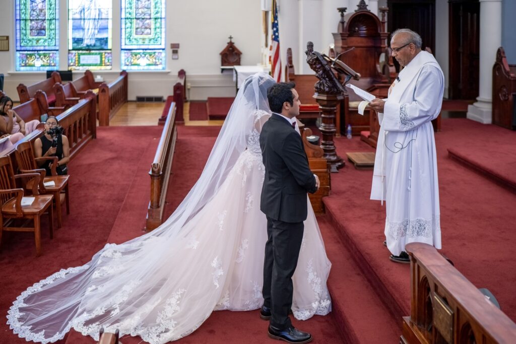 A couple standing before an officiant inside a church.