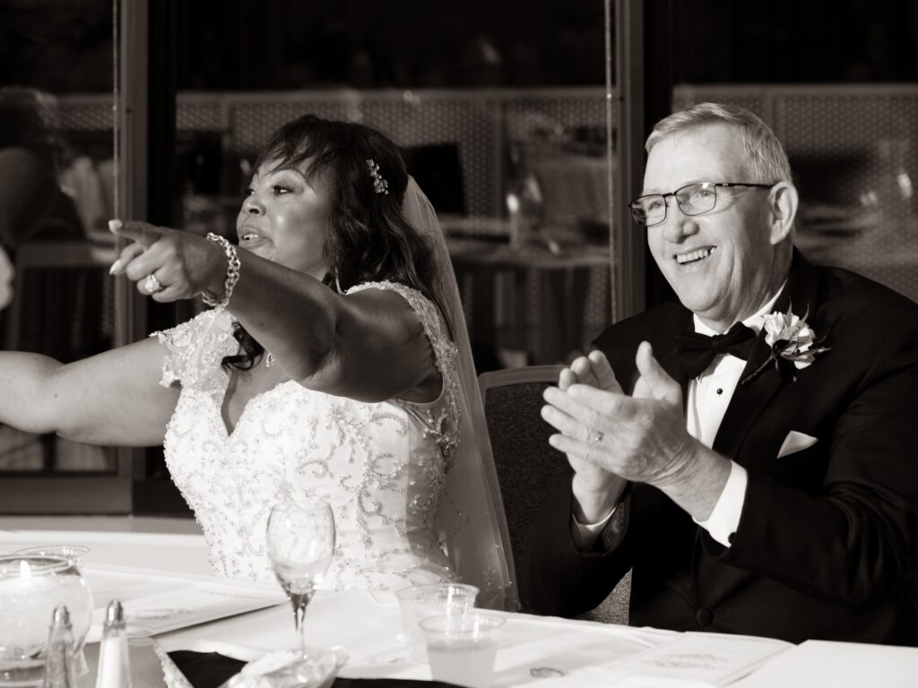 A couple smiling and gesturing during a celebration, in black and white.