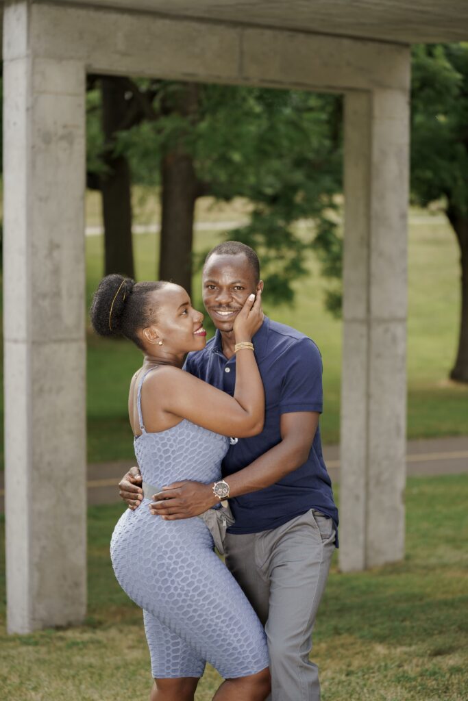 A couple embracing beneath a stone garden structure.