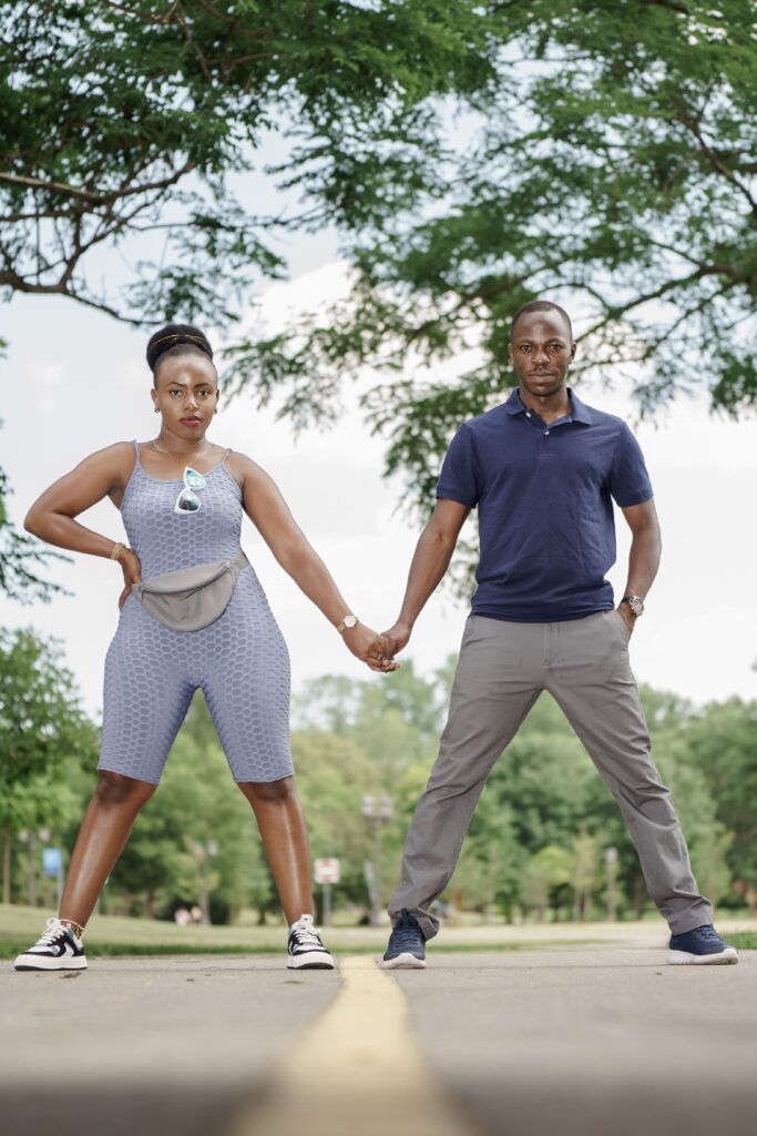 A couple holding hands on a tree-lined path.