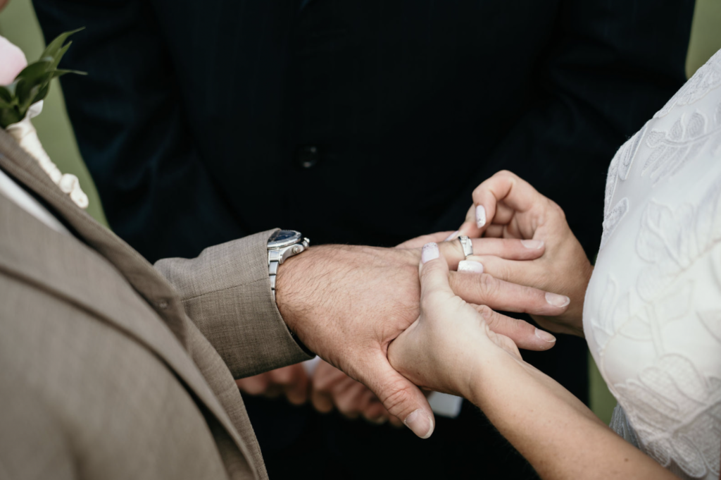 Close-up of a wedding ring being placed on the groom’s hand.