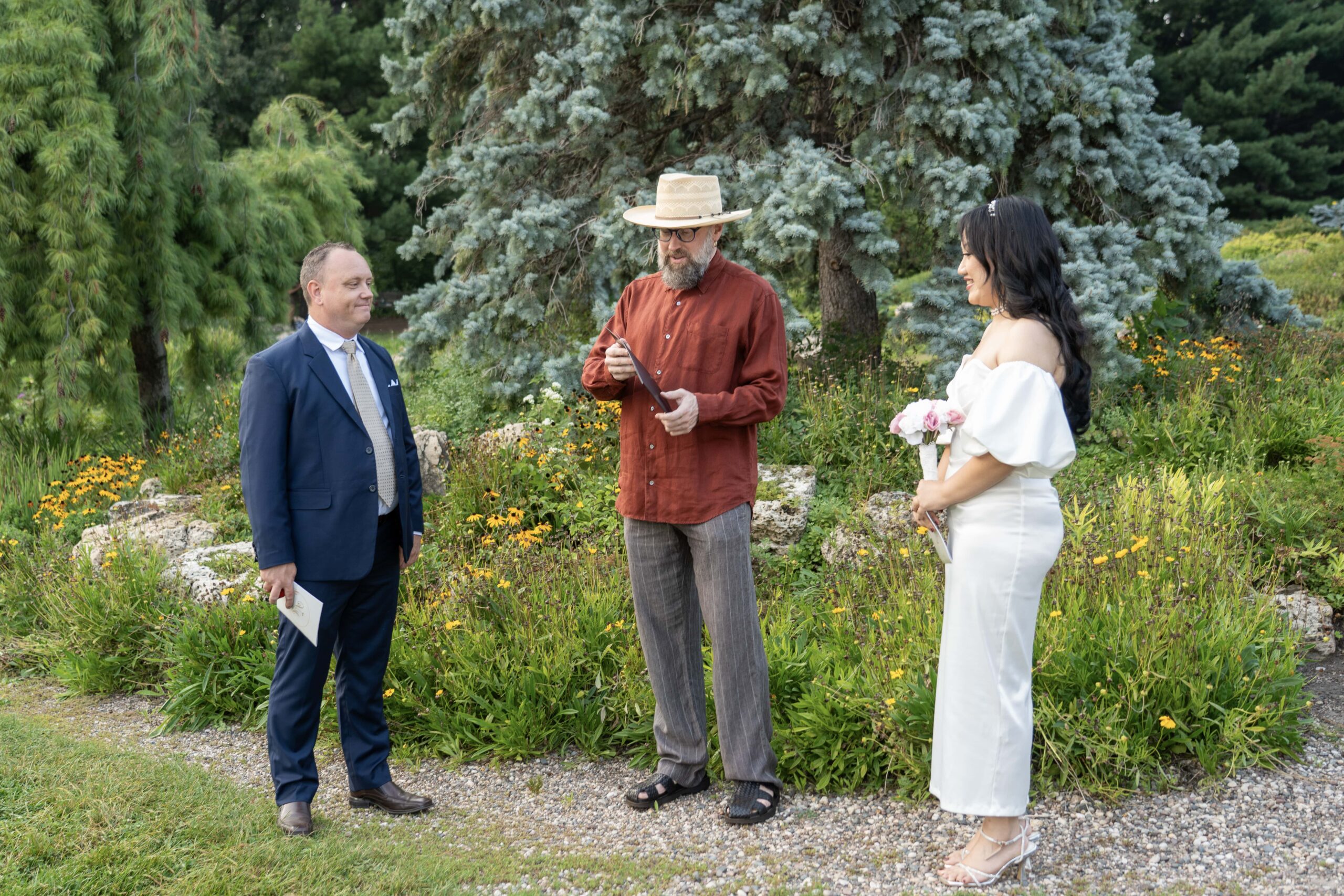 Wide view of a couple and officiant during an outdoor wedding ceremony.
