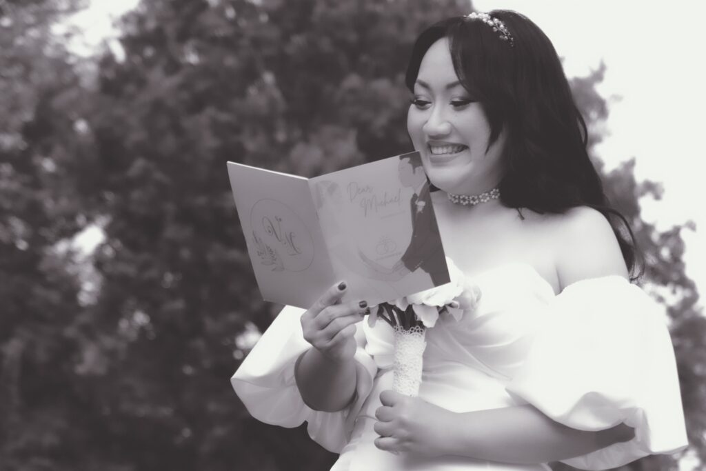 Bride smiling while reading her vows in a garden.