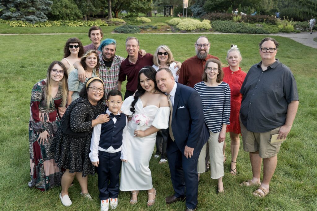 Wedding couple surrounded by a group of guests outdoors.