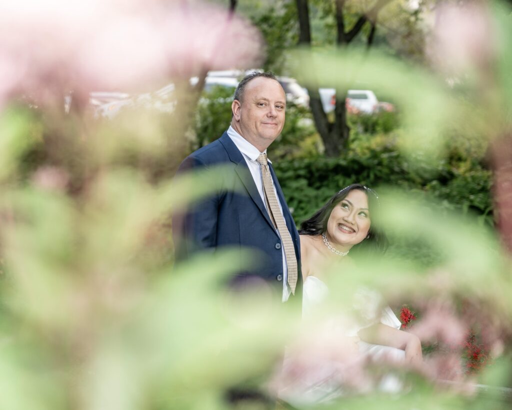 Wedding couple seen through flowers in the foreground.