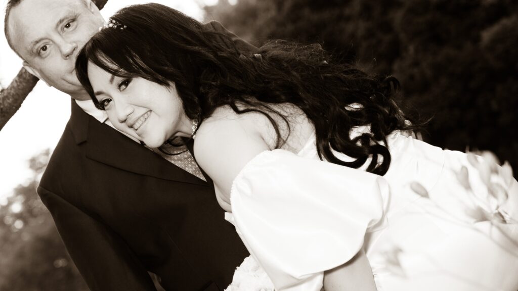 Black-and-white close portrait of the bride leaning towards the groom.
